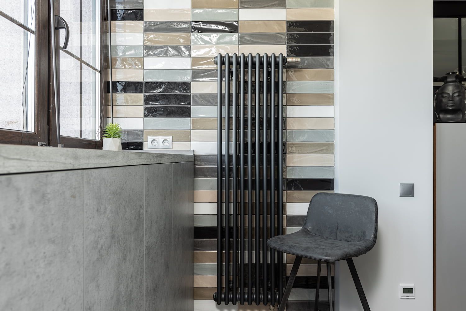 Ein dunkler Stuhl mit einer schwarzen Heizung an der Wand